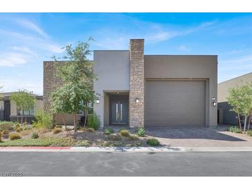 Contemporary home showcasing a two-car garage, stone accents, and desert-friendly landscaping at 9 Reverie Heights Ave, Henderson, NV 89011