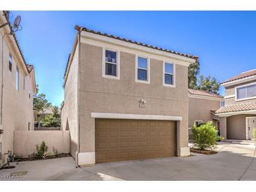 Tan home exterior featuring a two-car garage and neatly kept landscaping at 1425 Bow Creek Ct, Las Vegas, NV 89128