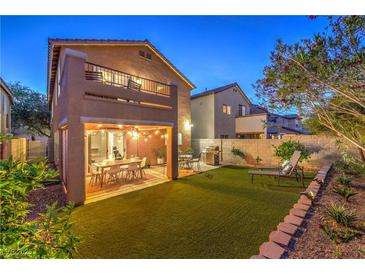 Inviting backyard with artificial grass, covered patio, outdoor furniture, and landscaped borders at 6546 American Flower St, Las Vegas, NV 89148