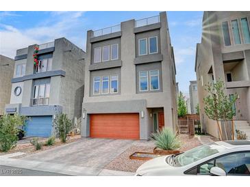 Contemporary gray home featuring an orange garage door, multiple windows, and low maintenance landscaping at 8087 Carpenter Creek Ave, Las Vegas, NV 89113