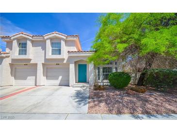 Charming two-story home boasts a striking turquoise door and a well-maintained, landscaped front yard at 1000 Grammy Dr, Las Vegas, NV 89145