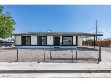 Charming single story home featuring fresh white paint, black trim, gravel yard, and chain link fence at 3040 Carroll St, North Las Vegas, NV 89030
