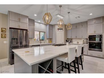 Bright kitchen with white marble countertops, stainless steel appliances, gray cabinetry, and decorative pendant lighting at 7613 Pulpit Rock Ct, Las Vegas, NV 89166