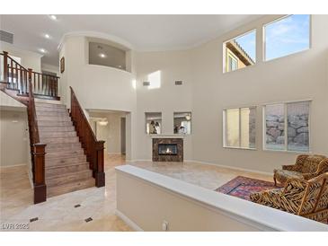 Bright living room with a staircase, fireplace, high ceilings, and several windows that provide lots of natural light at 1265 Vietti St, Henderson, NV 89012