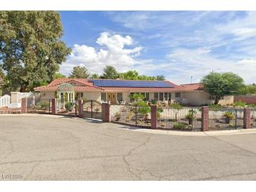 Charming single-story home featuring a terracotta roof and solar panels, surrounded by a beautifully landscaped yard and wrought iron fence at 2255 S Buffalo Dr, Las Vegas, NV 89117