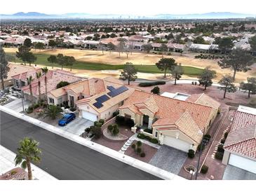 Stunning aerial view of houses with red tile roofs next to golf course with mountain and city views in the distance at 3004 Darby Falls Dr, Las Vegas, NV 89134