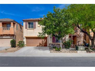 Two-story home featuring a brown two-car garage, tan stucco, stone accents, and front yard trees at 8988 Winchester Ridge St, Las Vegas, NV 89139