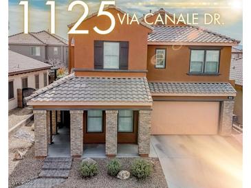 Two-story home featuring a tile roof, a covered front porch with stone pillars, and a two car garage at 1125 Via Canale Dr, Henderson, NV 89011