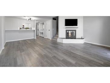 Spacious living room featuring new gray flooring, fireplace with mounted television, and an open bar to the kitchen at 6442 Ironbark Ln, Las Vegas, NV 89107
