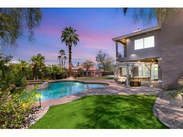 Backyard pool with manicured lawn, spa, and outdoor seating, perfect for entertaining at 7520 Captains Harbor Dr, Las Vegas, NV 89117