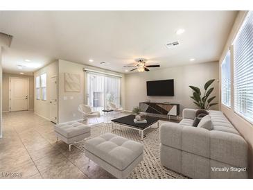 Bright, open-plan living room with a large window, ceiling fan, and tile flooring at 9655 Shadow Cliff Ave, Las Vegas, NV 89166