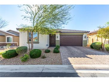 Charming single-story home showcasing a well-manicured lawn and a two-car garage, complete with stone accents and desert landscaping at 5633 Alitak Bay St, North Las Vegas, NV 89081