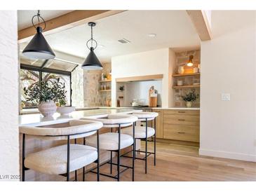 Bright kitchen features a quartz island, modern lighting fixtures, stone accents, and wood beams at 5741 S Pearl St, Las Vegas, NV 89120