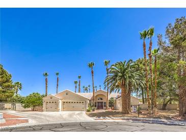 Charming single-story home with a three-car garage and mature palm tree landscaping set against a clear blue sky at 7300 Breezy Night Ct, Las Vegas, NV 89129