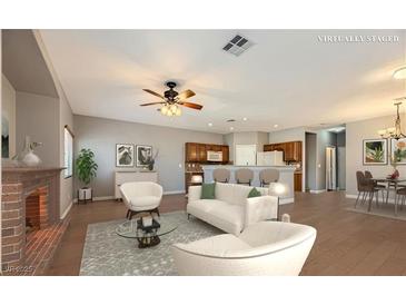 Bright, open living area with hardwood floors, fireplace, ceiling fan, and bar seating in the kitchen at 8728 Tom Noon Ave # 103, Las Vegas, NV 89178