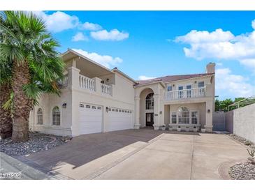 Stucco home featuring a three-car garage, balcony, red tile roof, and mature palm tree at 2595 Aviv Ct, Las Vegas, NV 89121