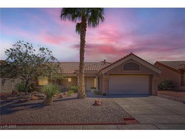Charming single-story home with a well-manicured front yard, complemented by a mature palm tree at sunset at 3012 Haddon Dr, Las Vegas, NV 89134