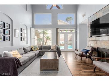 Bright living room featuring a gray sectional sofa, high ceilings, and a fireplace with a stone surround at 3079 Paseo Mountain Ave, Henderson, NV 89052
