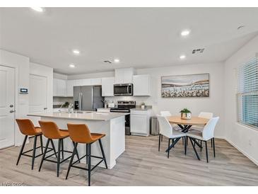 Bright eat-in kitchen features stainless appliances, white cabinetry, and three-seat island at 3762 Sonrisa Vista Ave, Henderson, NV 89044