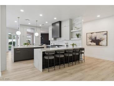 Modern kitchen with stainless steel appliances, gray cabinets, a waterfall island, and wood floors at 4944 Spanish Heights Dr, Las Vegas, NV 89148