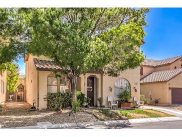 Inviting two-story home with a tile roof, mature tree, and cozy front porch seating area at 7352 Rietz Canyon St, Las Vegas, NV 89131