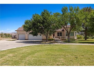 Charming home featuring a large front lawn, mature trees, and a three-car garage at 1470 St Joseph St, Overton, NV 89040