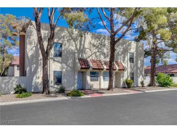 Charming townhome featuring a stucco facade, red tile accents, and mature landscaping at 611 Spyglass Ln, Las Vegas, NV 89107