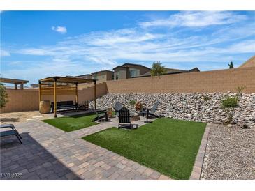 Inviting backyard featuring a pergola, fire pit area with chairs, and low-maintenance landscaping at 9641 Rankin Ridge Ct, Las Vegas, NV 89178