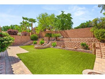 Expansive backyard features lush green turf, tiered retaining walls, and a charming stone fire pit at 11764 Golden Moments Ave, Las Vegas, NV 89138