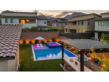 Stunning backyard featuring a sparkling pool, integrated spa, stylish pergola, and built-in outdoor kitchen, perfect for entertaining at 11954 Camden Ridge Ct, Las Vegas, NV 89138