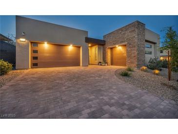 Modern home showcasing a driveway with a three car garage featuring stylish doors and beautiful stone accents at 11954 Camden Ridge Ct, Las Vegas, NV 89138