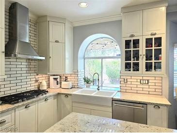 Bright kitchen featuring white cabinets, subway tile backsplash, and stainless steel appliances, with a view from the sink at 2434 Amoretti St, Henderson, NV 89052