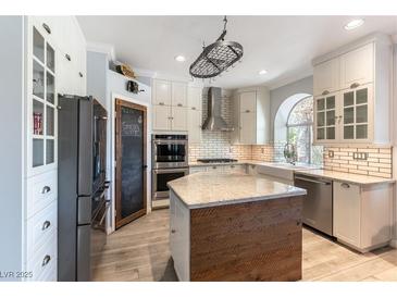 Bright kitchen with wooden floors, stainless steel appliances, and white cabinets at 2434 Amoretti St, Henderson, NV 89052