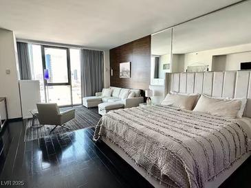 Modern bedroom featuring floor-to-ceiling windows, dark wood floors and a comfortable sitting area at 4381 W Flamingo Rd # 1504, Las Vegas, NV 89103