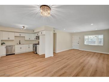 Open concept living room with modern kitchen, wood floors, and ample natural light at 4804 Apawana Ln, Las Vegas, NV 89108