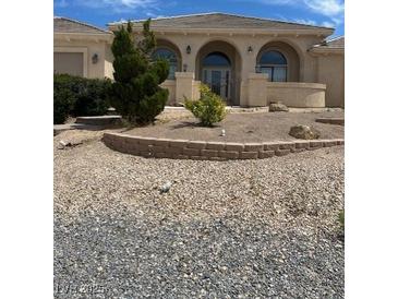 Charming home featuring an arched entry and low maintenance desert landscaping for an appealing and water-wise facade at 6841 Longmeadow Dr, Pahrump, NV 89061