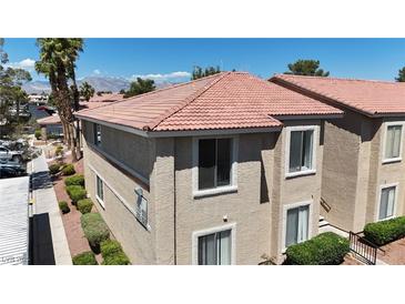 Tan two-story condo with a terra cotta colored roof and desert landscaping on a sunny day at 7200 Pirates Cove Rd # 2025, Las Vegas, NV 89145