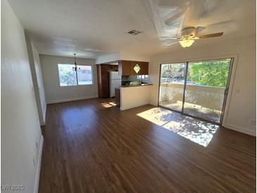 Bright living room with wood floors, ceiling fan, and sliding glass doors to a balcony at 7200 Pirates Cove Rd # 2025, Las Vegas, NV 89145