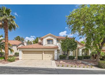 Charming two-story home with a red tile roof, lush landscaping, and a spacious three-car garage at 8320 Opal Cove Dr, Las Vegas, NV 89128