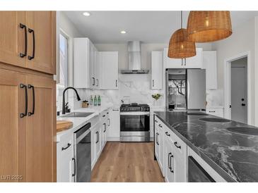Modern kitchen features stainless steel appliances, white cabinets, and a marble backsplash at 1551 Boundary Peak Way, Las Vegas, NV 89135