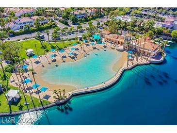 Aerial view of the community pool, featuring a sandy beach entry and surrounding palm trees at 8404 Shore Breeze Dr, Las Vegas, NV 89128