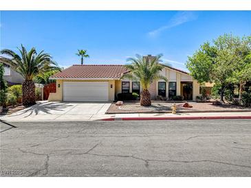 Charming single-story home with a lush front yard, palm trees, and a two-car garage at 8705 Orvieto Dr, Las Vegas, NV 89117