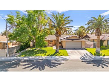Charming single-story home featuring a well-manicured lawn, mature trees, and a two-car garage at 2426 La Pluma St, Henderson, NV 89014