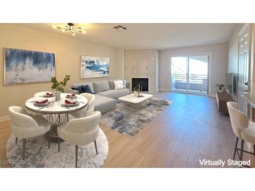 Bright living room features a fireplace, light wood floors, modern decor, and sliding glass doors at 6853 Tamarus St # 202, Las Vegas, NV 89119