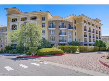 Beautiful condo building exterior with manicured landscaping and a decorative brick driveway entrance at 29 Montelago Blvd # 213, Henderson, NV 89011