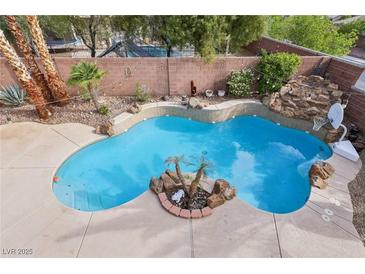 Beautiful backyard pool area with decorative rock features, palm trees and cool, refreshing water at 4042 Keefe Falls Ct, North Las Vegas, NV 89085