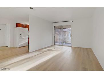 Bright living room with wood-look floors and sliding glass doors to a balcony at 4310 Sandy River Dr # 70, Las Vegas, NV 89103