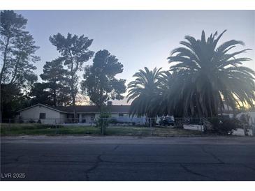 Charming single-story home with mature palm trees and a fenced front yard, bathed in the soft light of dusk at 5910 Fannine Way, Las Vegas, NV 89130