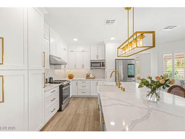 Bright kitchen with stainless steel appliances, white cabinetry, and large center island with marble countertops at 9615 Sedona Hills Ct, Las Vegas, NV 89147
