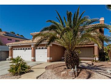 Charming home with a three-car garage and well-maintained landscaping and desert landscaping with a palm tree in the yard at 1066 Aspen Valley Ave, Las Vegas, NV 89123